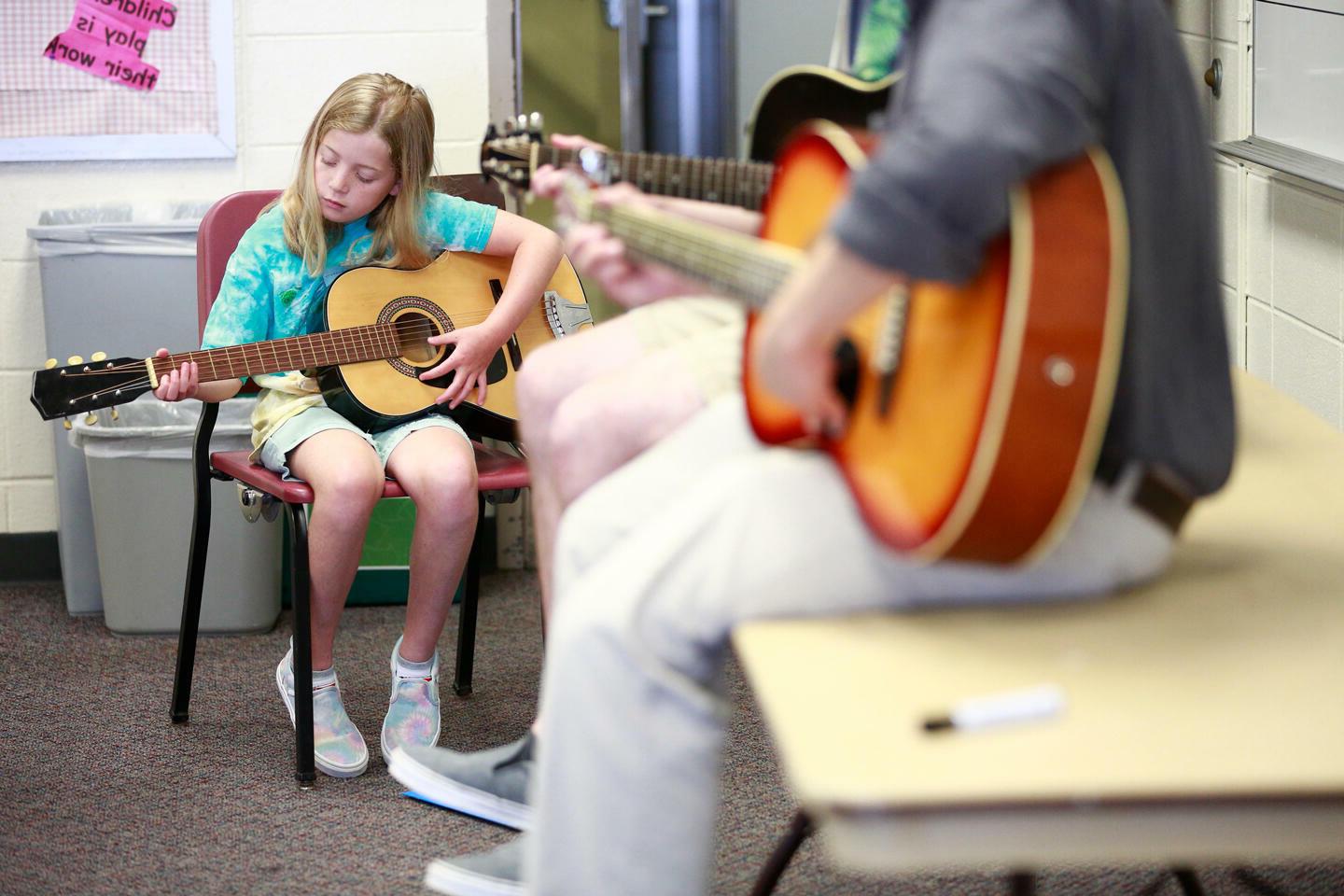 学生在教孩子弹吉他